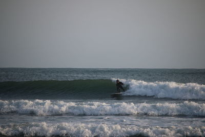 Man surfing in sea against clear sky