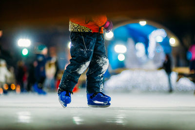 Low section of man ice-skating at night