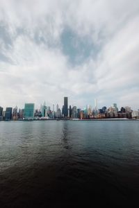 Sea by buildings against sky in city