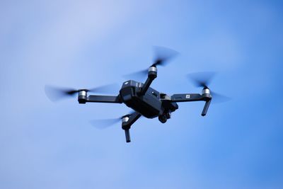 Low angle view of airplane flying against clear blue sky