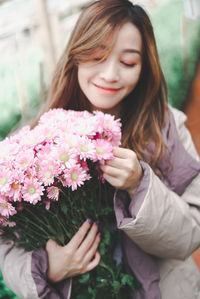 Beautiful young woman holding pink flowering plants
