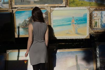 Rear view of woman looking through glass window