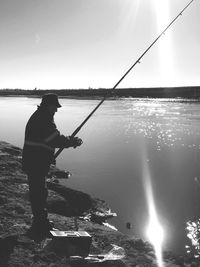 Man fishing in lake against sky