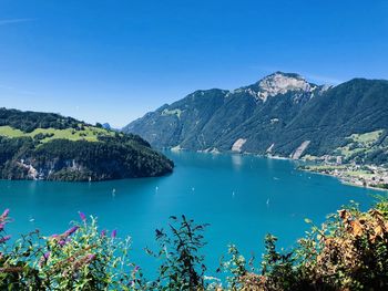 Scenic view of lake and mountains against clear blue sky