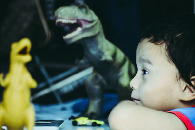 Close-up of toddler with dinosaur figurines at home