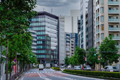 Road by buildings in city against sky