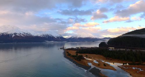 Scenic view of lake by snowcapped mountains against sky during winter