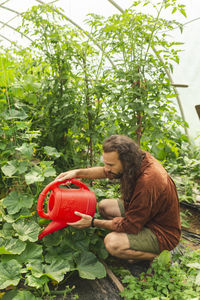 Farmer watering plants in greenhouse