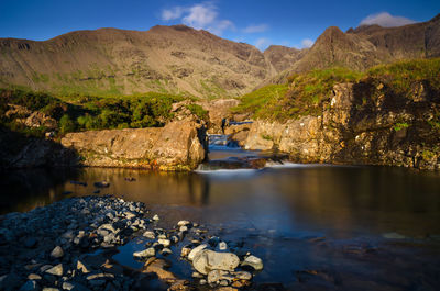 Scenic view of river by mountains against sky