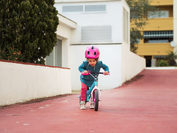 Little girl on bicycle near modern apartment building