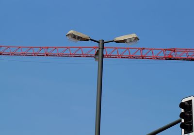 Low angle view of crane against clear blue sky