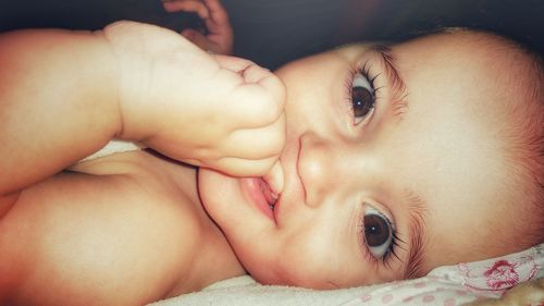 Close-up portrait of cute baby lying on bed