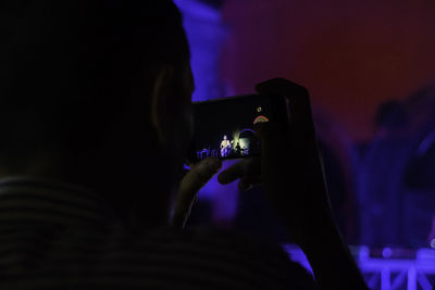 Close-up of man photographing at music concert