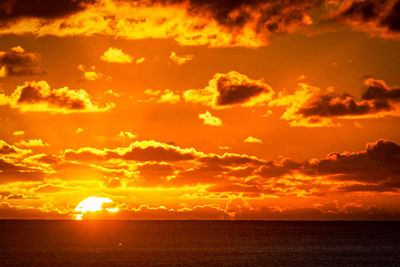 Scenic view of sea against dramatic sky during sunset