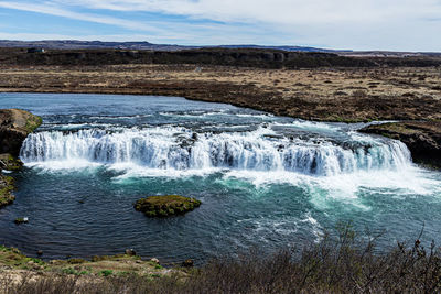 Scenic view of waterfall against sky