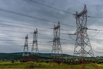 Electricity pylon on field against sky