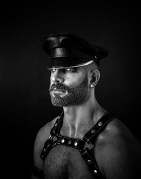 Portrait of man wearing leather harness against black background