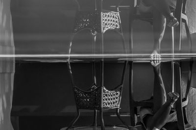 Upside down image of person sitting in chair with reflection on glass