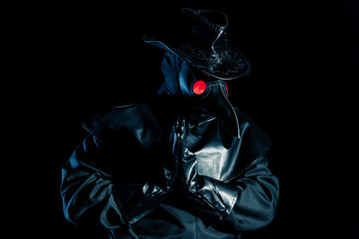 Midsection of man wearing mask against black background