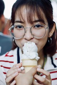 Cropped hand of person feeding woman ice cream