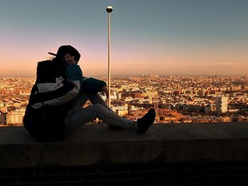 People sitting on city against sky during sunset