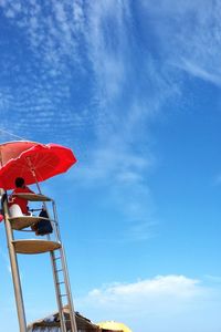 Low angle view of red flag against blue sky