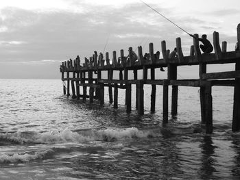 Wooden posts on pier over sea against sky