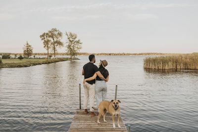 Man with dog on lake against sky