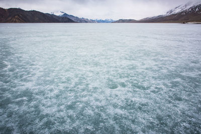 Scenic view of sea and snowcapped mountains against sky