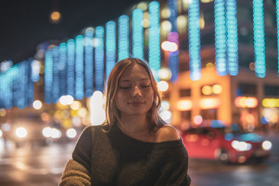 Fashionable young woman in city at night