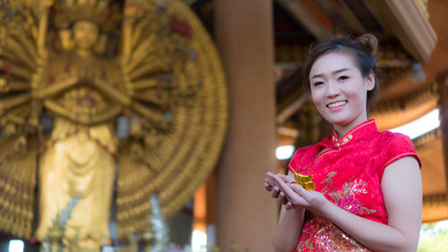 Close-up of smiling young woman standing against wall