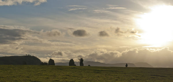 Scenic view of grassy field against sky at sunset