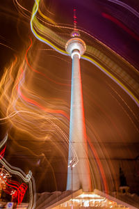 Low angle view of light trails by fernsehturm against sky