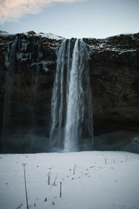 Scenic view of waterfall against sky during winter