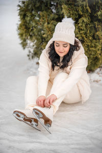 Portrait of young woman sitting on snow covered field