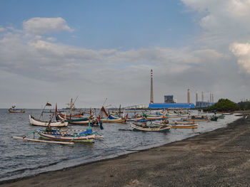 Fishing boats moored on sea against sky