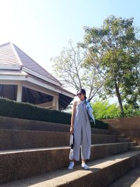 Portrait of happy woman standing on steps against sky