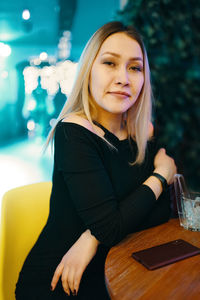 Portrait of smiling young woman sitting on table