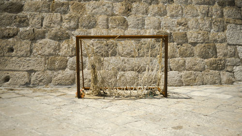 Old stone wall by street with rusty football goal