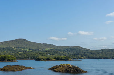 Scenic view of sea by mountains against sky