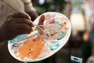 Cropped hand of woman painting on table