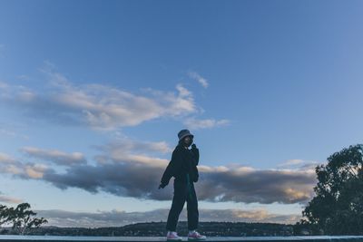 Woman standing on wall against sky