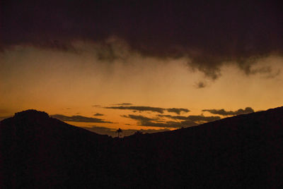 Low angle view of silhouette mountain against dramatic sky
