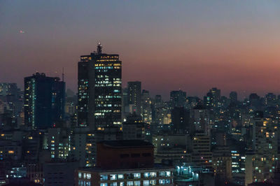 Illuminated cityscape against sky at night