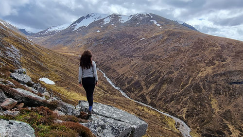 Rear view of woman walking on mountain against sky