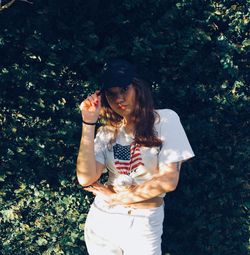 Young woman wearing hat standing against plants