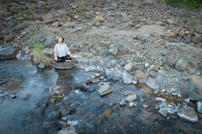 Man sitting on rock by river