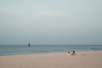 People on beach against clear sky