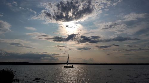 Silhouette sailboat in sea against sky during sunset