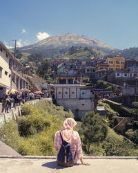 Rear view of people sitting outside building against sky